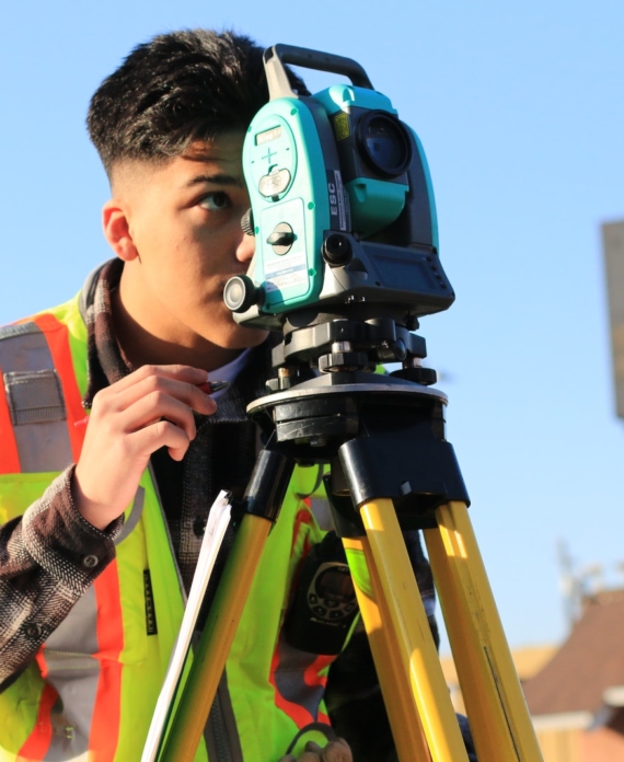 man in gray and orange jacket holding green and black dslr camera during daytime